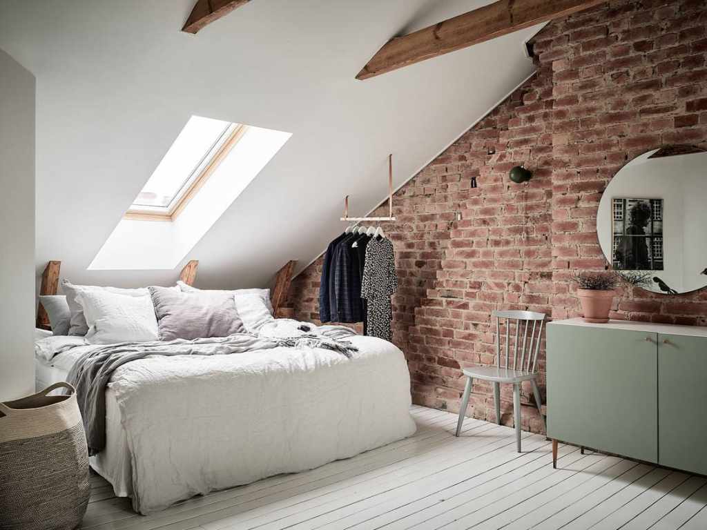 An attic bedroom with an exposed brick wall