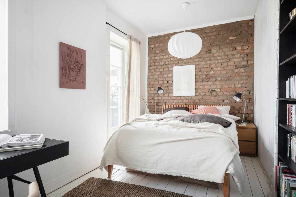 A bright and white bedroom with an exposed brick wall
