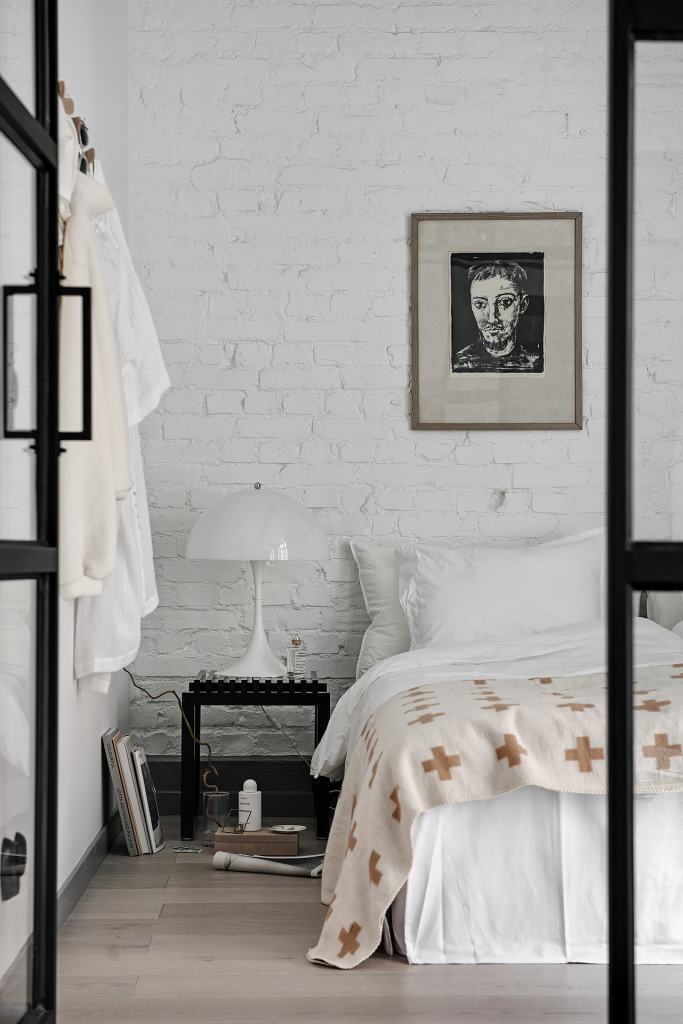 A white-painted brick wall behind the bed in a modern industrial style bedroom