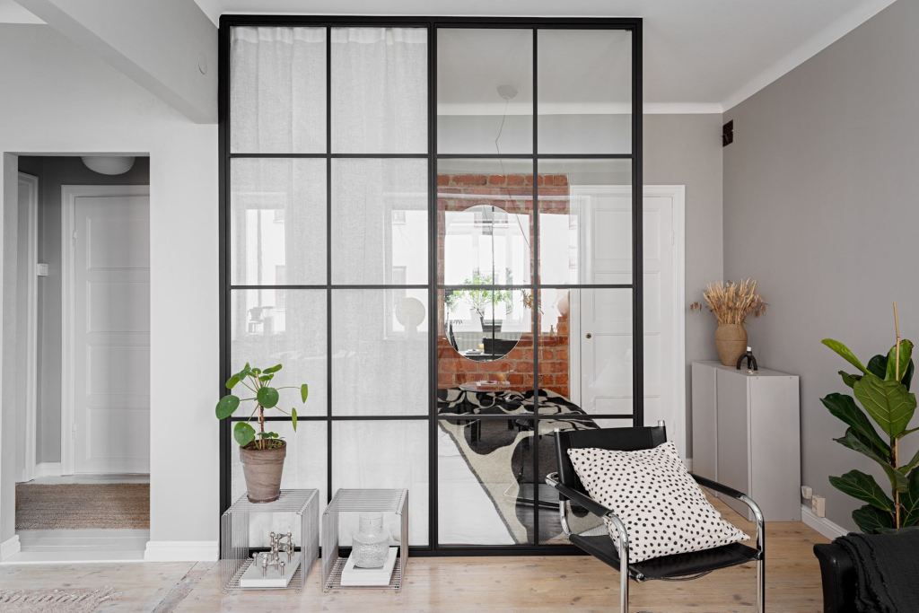 A studio home with a half glass partition wall to divide the space, with a curtain behind it to create privacy