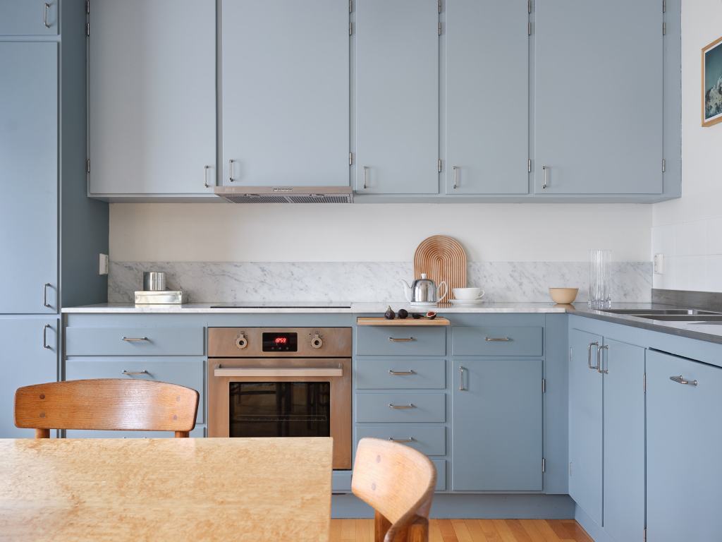 A light blue kitchen with chrome hardware and a vintage dining table