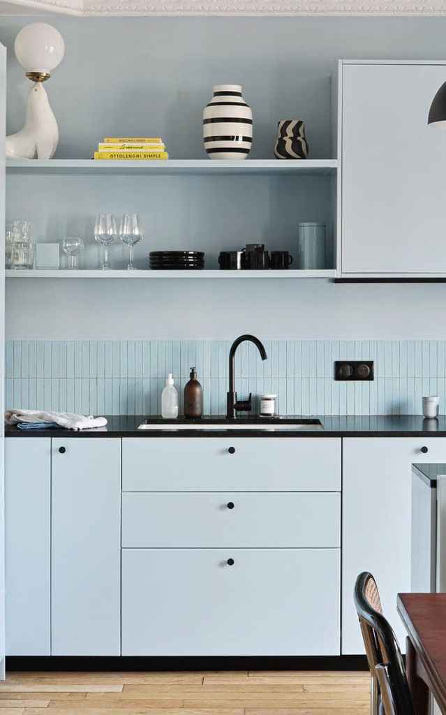 Light blue kitchen cabinets paired with a blue subway tile backsplash, black countertops and black hardware
