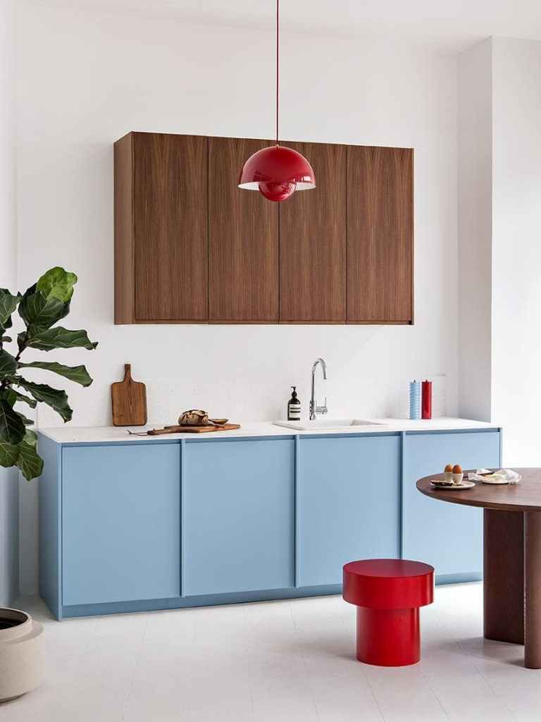 A modern two-tone kitchen with blue and dark wood kitchen cabinets, red accents