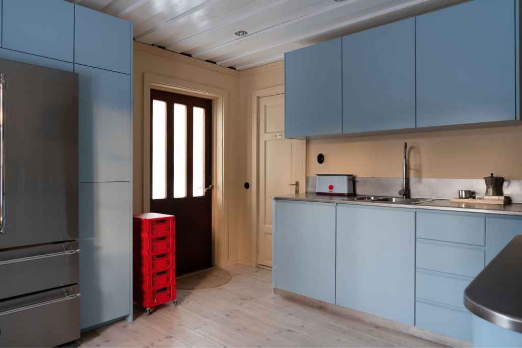 A ligt blue kitchen with beige walls and a pop of red