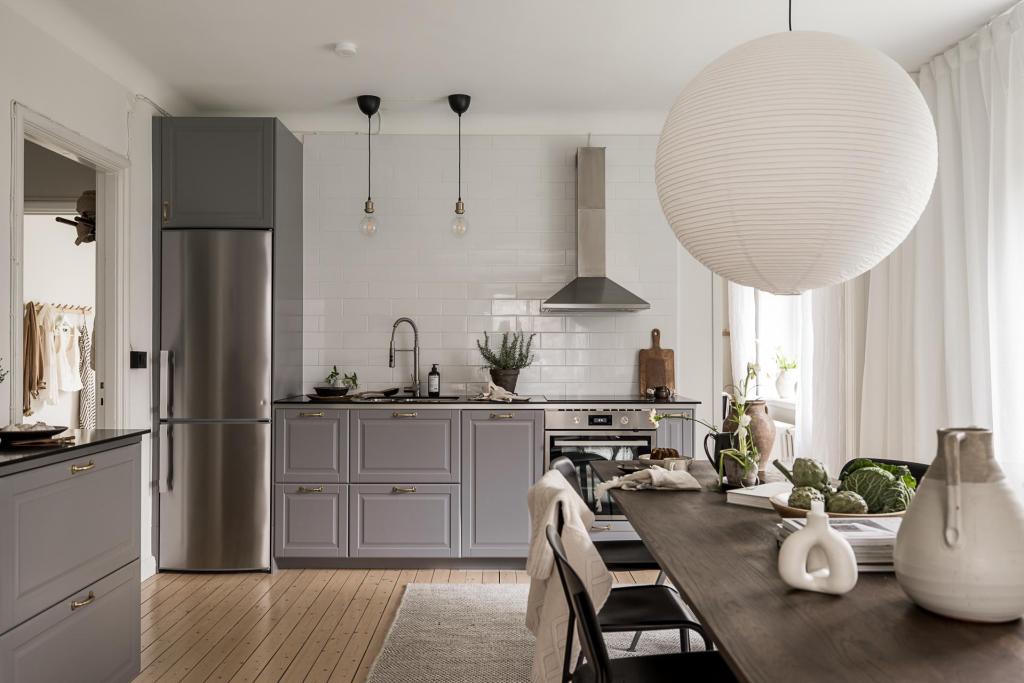 a kitchen with dark grey cabinets, stainless steel appliances and brass hardware, dark oak dining table with black chairs