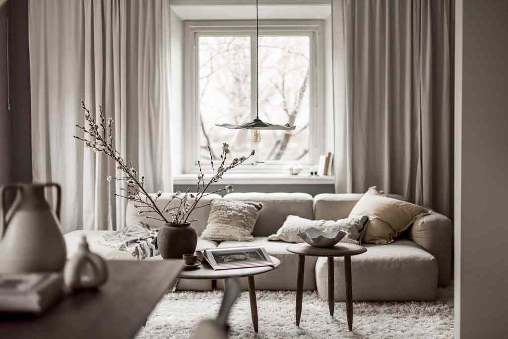 A living room with dark grey walls, a beige fabric sofa and dark oak coffee tables