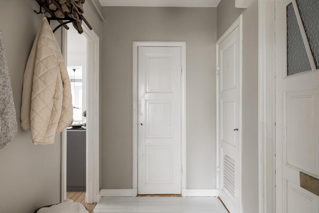 A hallway with warm grey walls and white painted hardwood flooring