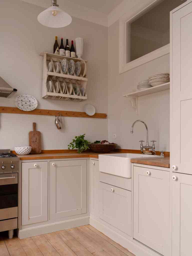 A beige farmhouse kitchen with butcher block countertops and white porcelain hardware