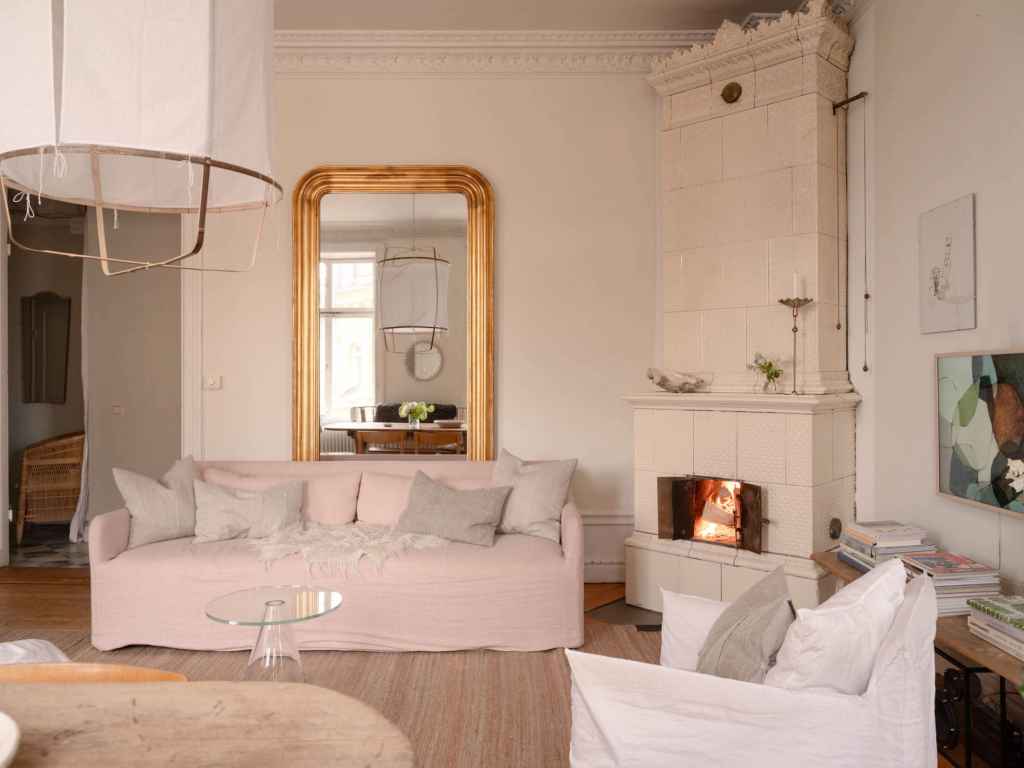 A living room with off-white walls and warm wood tones, pink sofa