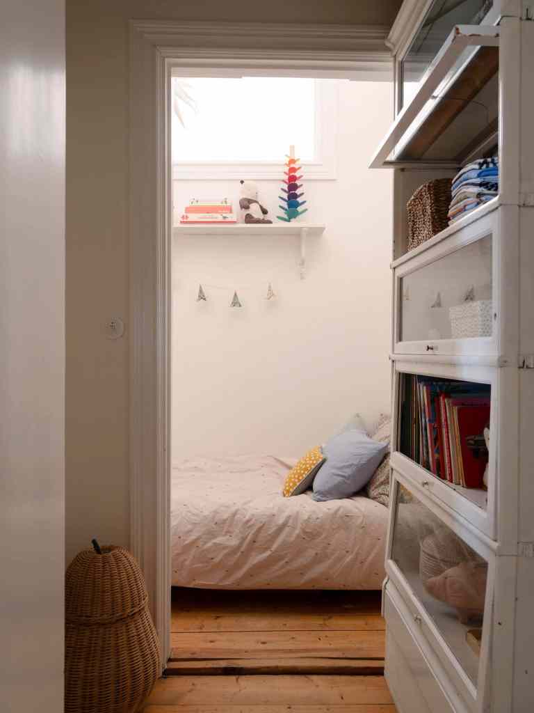 A tiny kids room with a window towards the kitchen