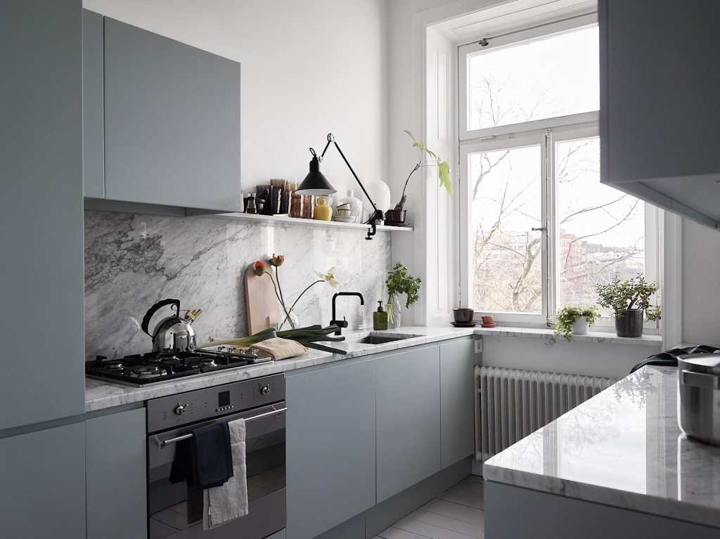 A grey galley kitchen whit a white marble countertop and backsplash