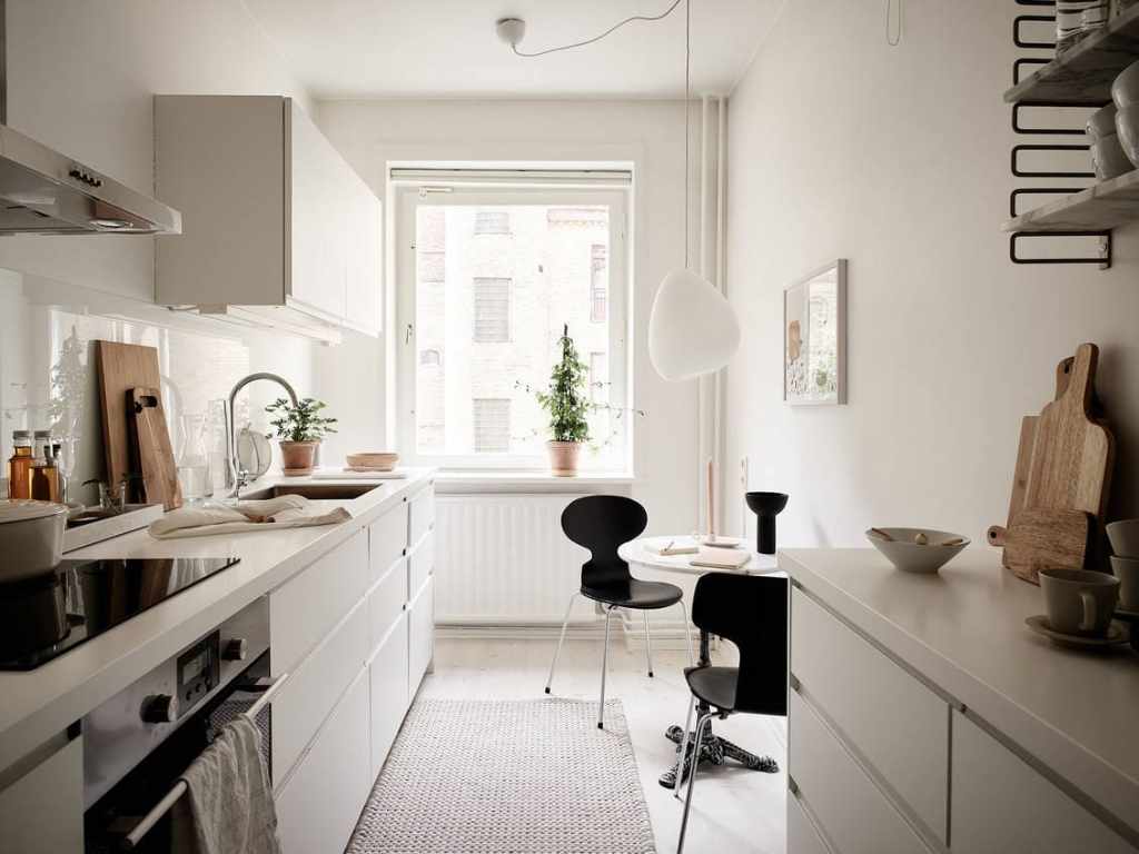 A white galley kitchen with a black dining area