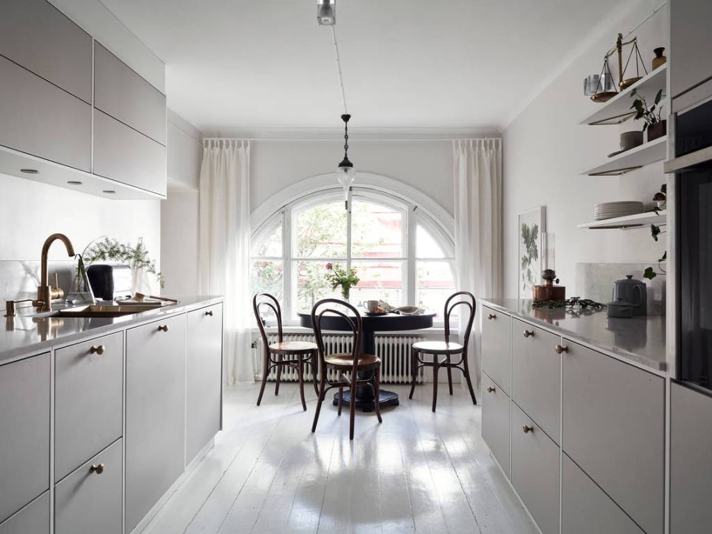 A spacious galley kitchen with white floors and a rounded window