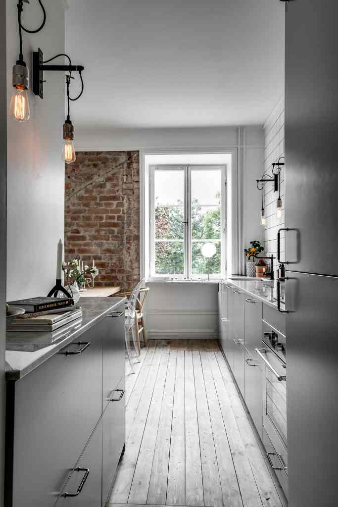 A narrow galley kitchen with task lighting on the wall