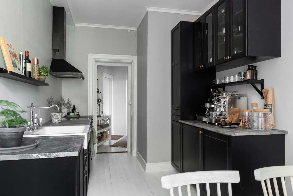 A black galley kitchen with grey marble countertops and grey walls