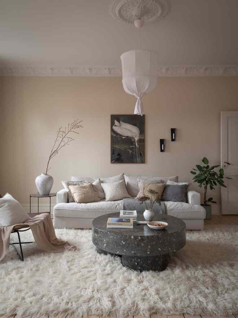 A cream living room with a black stone coffee table, white couch and black accents