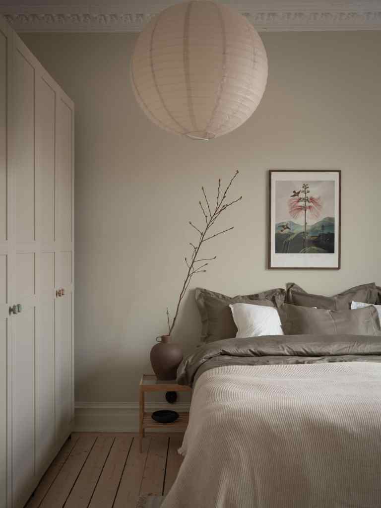 A bedroom with an eggshell wall color, a wardrobe in the same color, and a subtle color palette