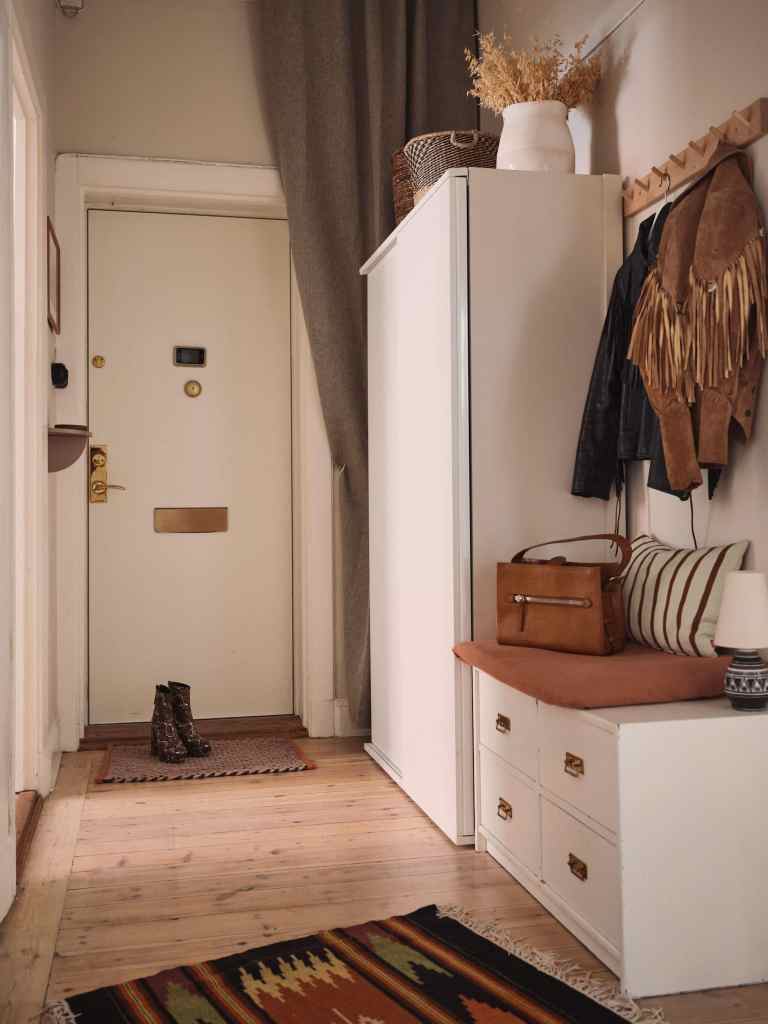 A small hallway with an asymmetrical floor plan and a combination of storage with seating