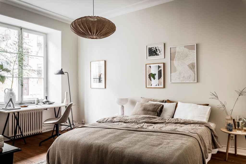 A bedroom with beige tones and off-white walls finished off with a simple gallery wall