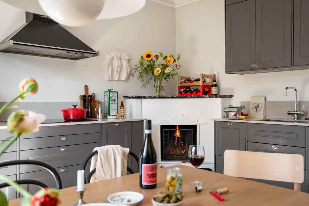 A grey shaker kitchen with a fireplace in the corner
