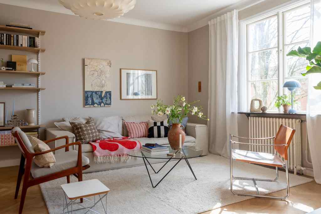 A living room with warm grey walls and bright pops of red