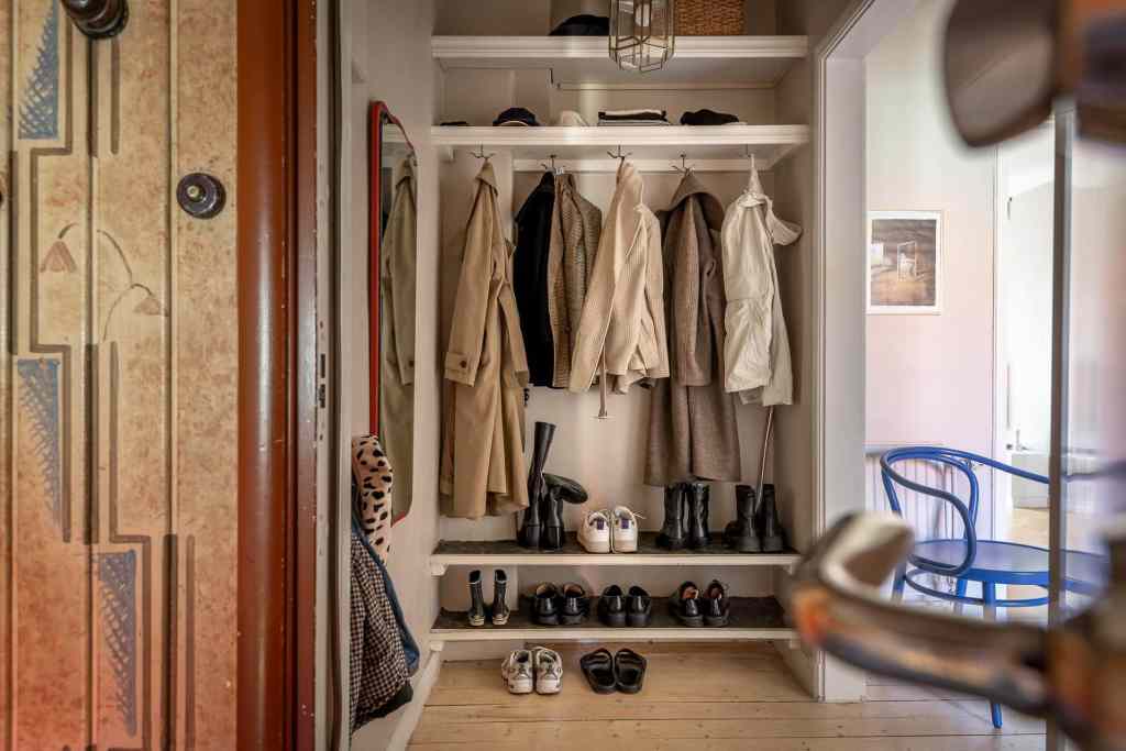A hallway with custom storage shelving for shoes and jackets