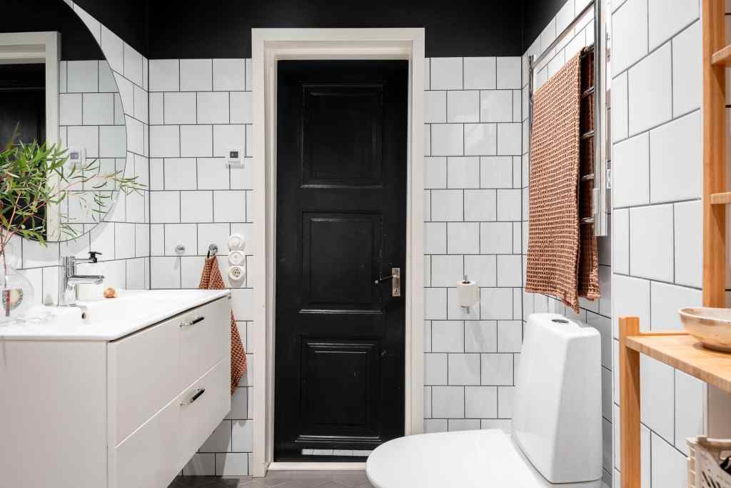 A bathroom with white tiles on the wall and a black paint color on the ceiling