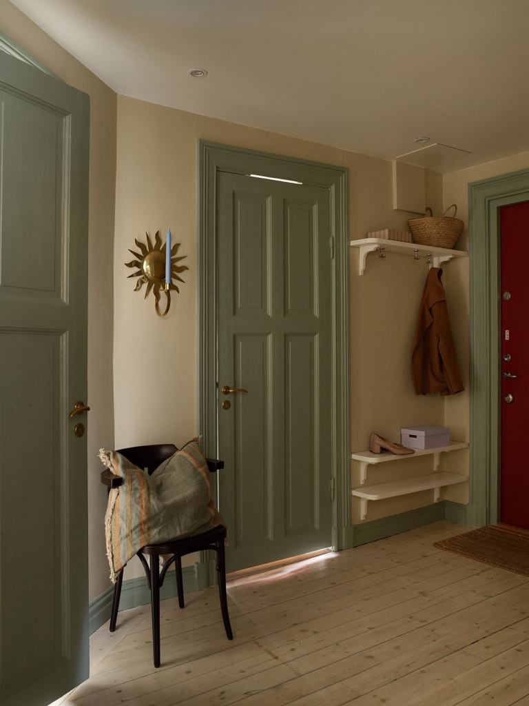 A hallway with beige walls and green doors