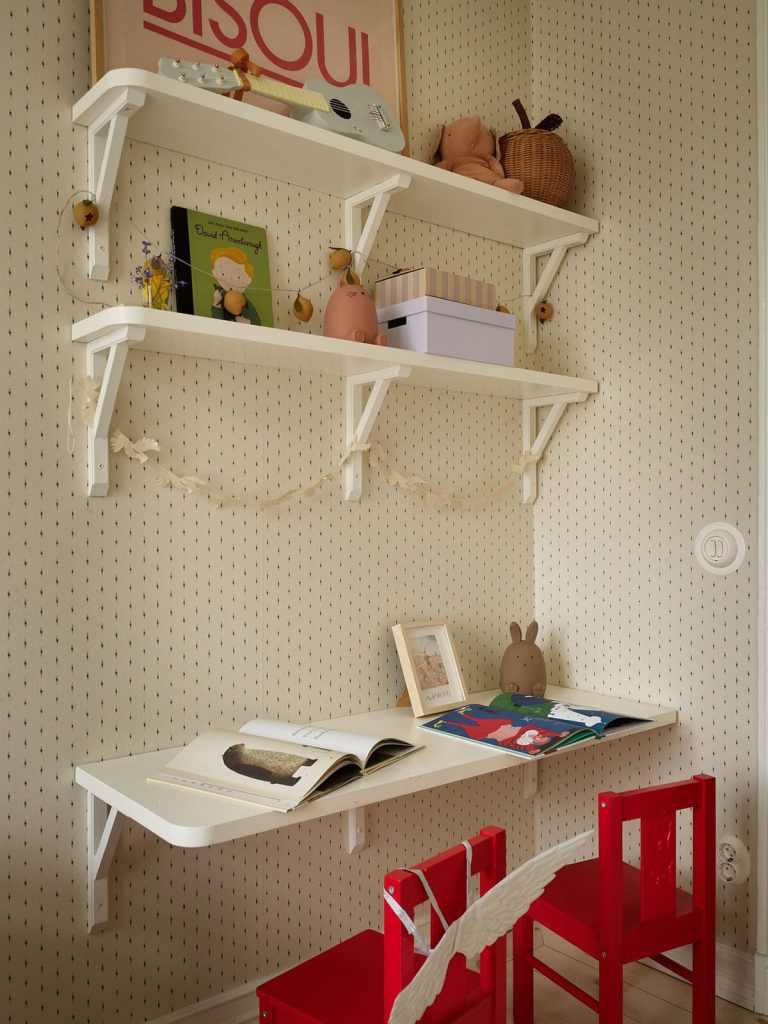 A kids room with a desk attached to the wall