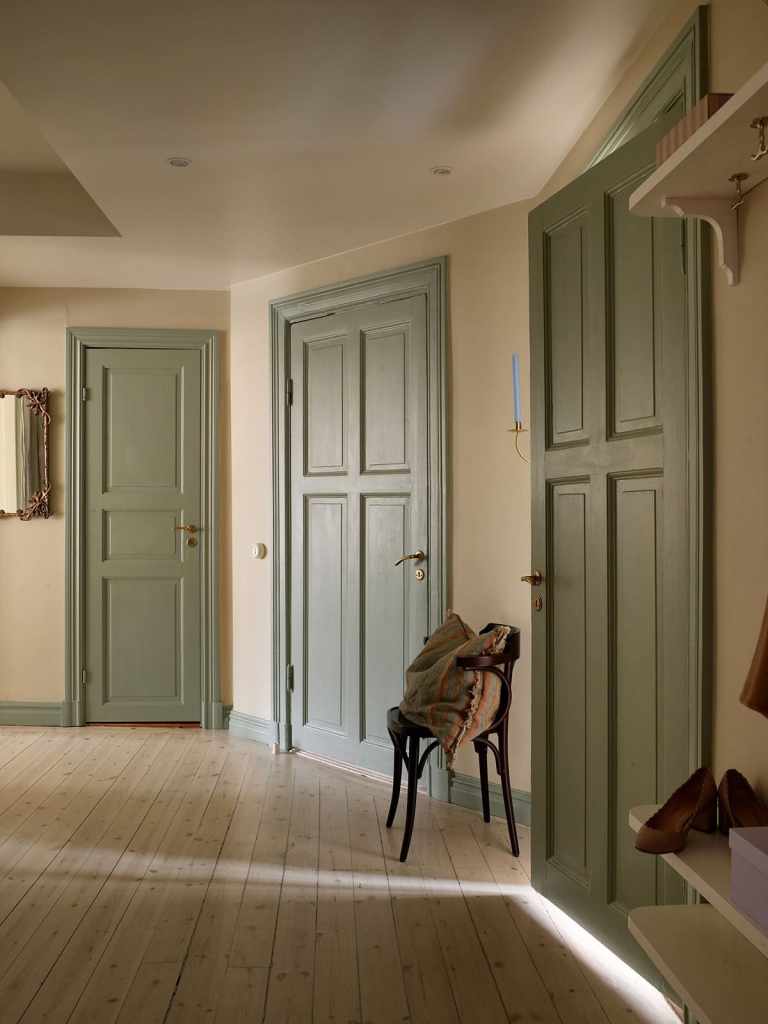 A hallway with beige walls and green doors