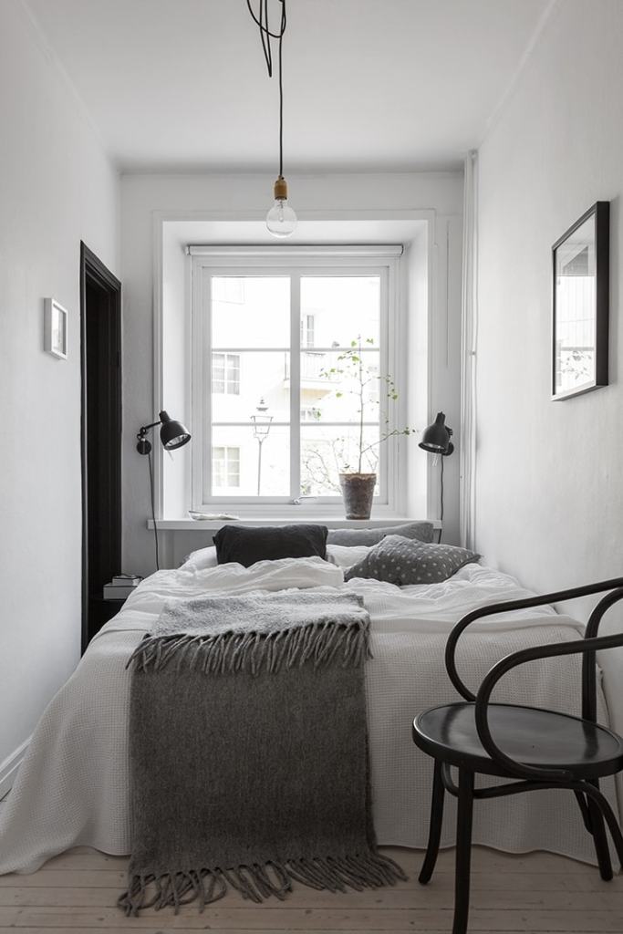 A small white bedroom with black accents and grey textiles