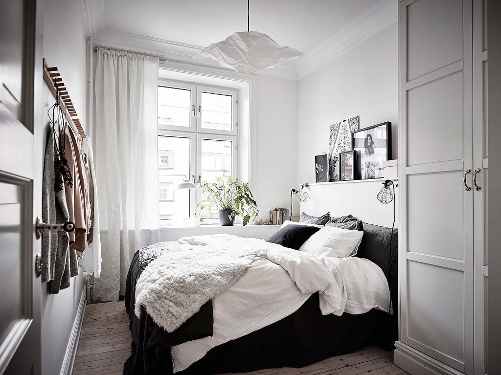 A black and white bedroom design with a gallery wall on a ledge above the bed