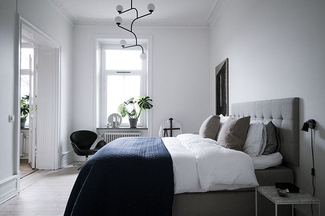 A monochrome bedroom with a blue blanket and grey fabric bed
