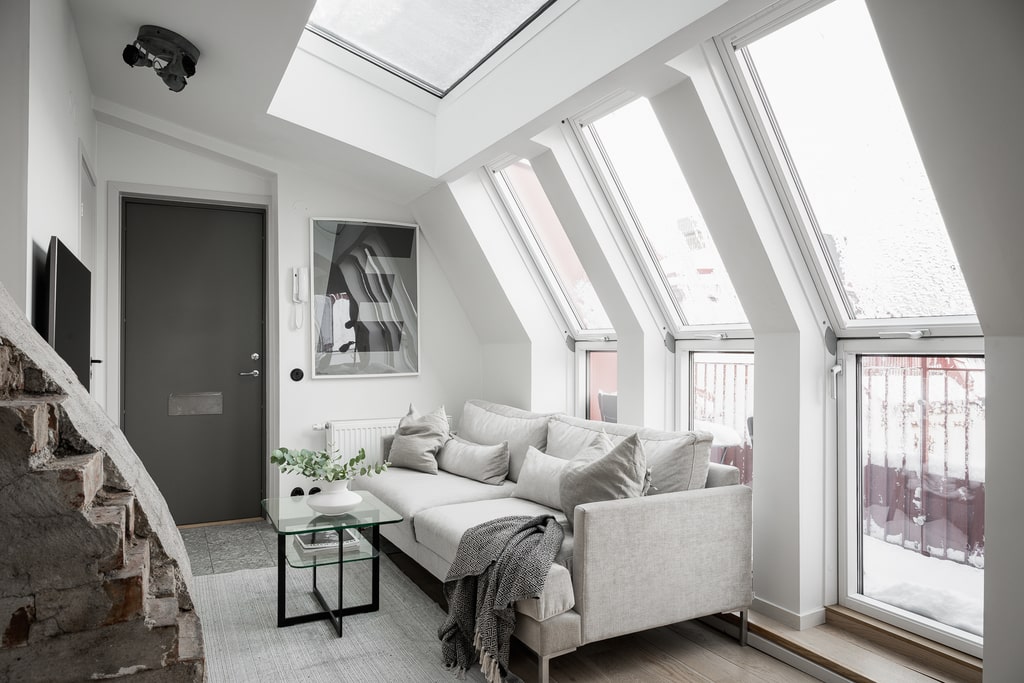 A living room with a light grey sofa and big skylight windows