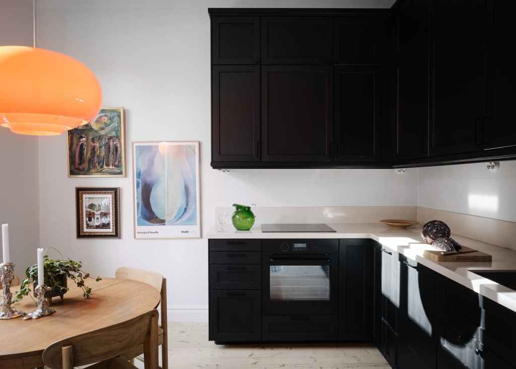 A black kitchen with light countertops and an L-shaped layout