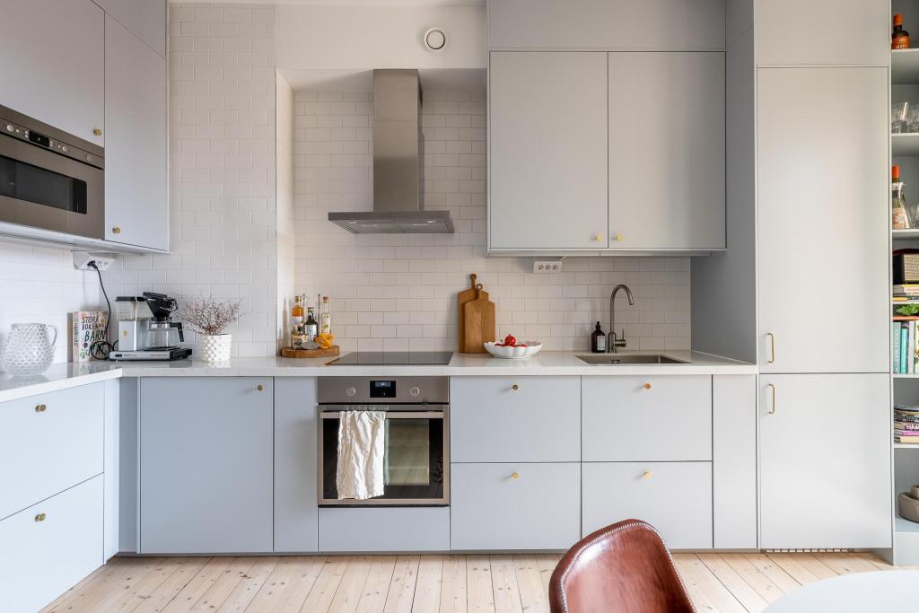 A simple grey kitchen with gold hardware and an L-shaped layout