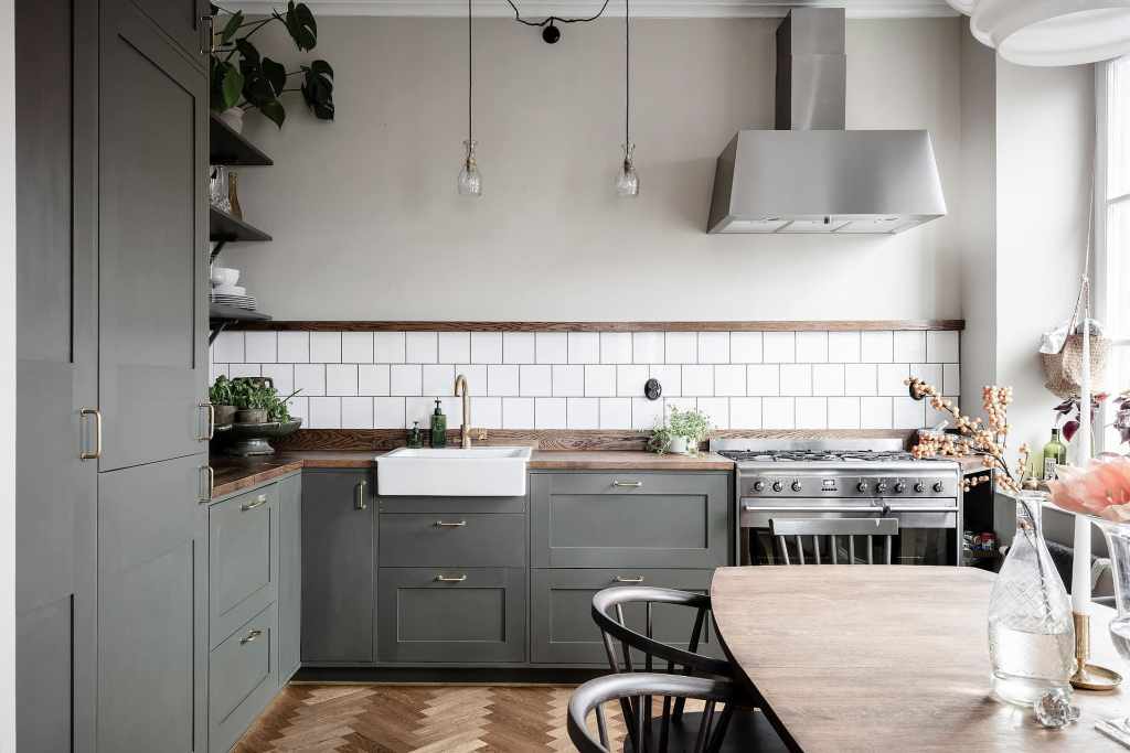 Am olive green kitchen in an L-shaped layout with wood countertops