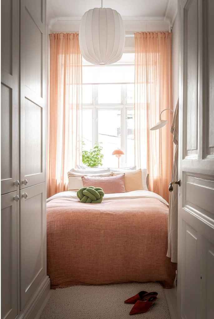 A small pink bedroom with green accents and a custom wardrobe