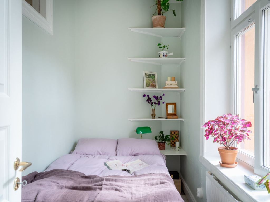 A small mint green bedroom with purple bedding