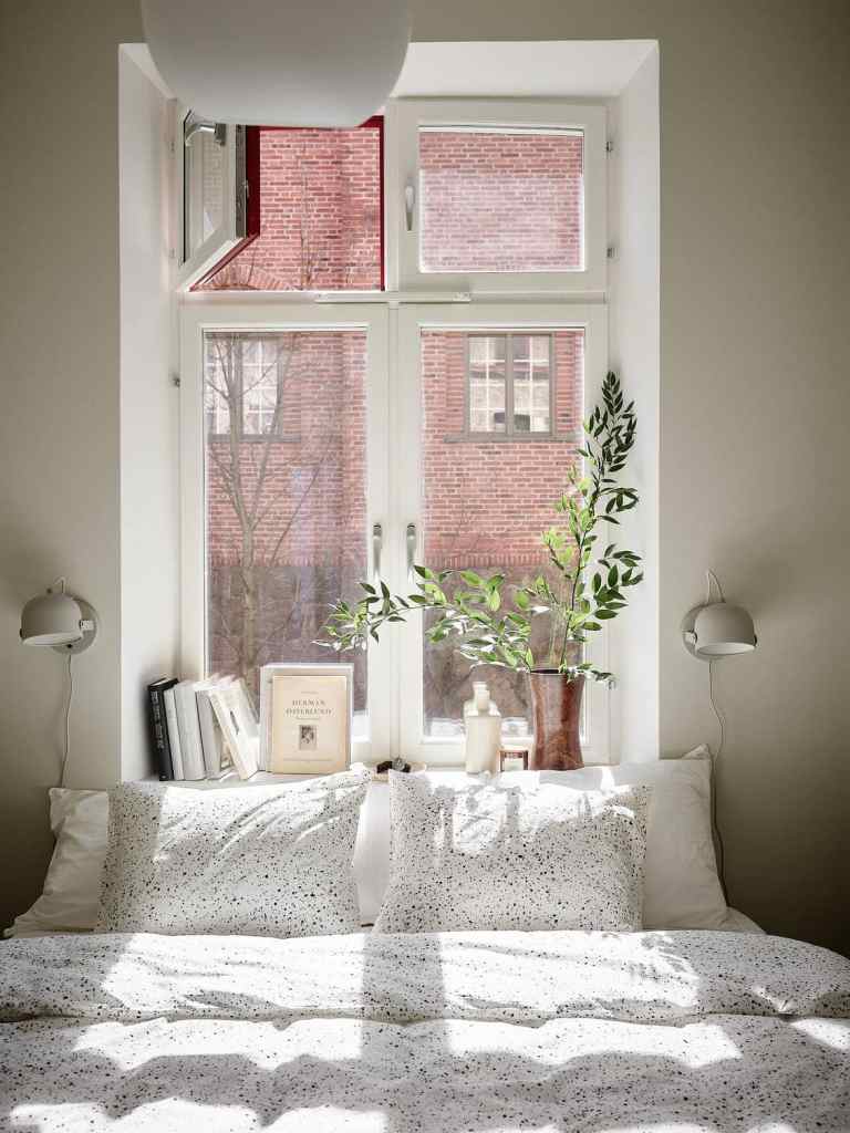 A small bedroom with greens on the window sill