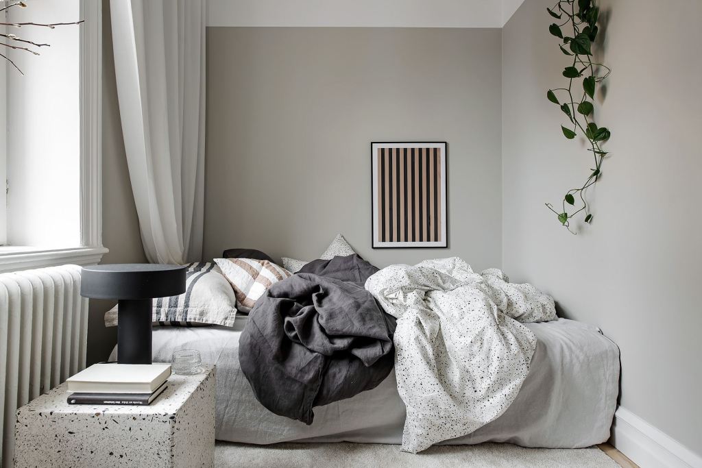 A small and neutral bedroom with black and white elements and a green plant
