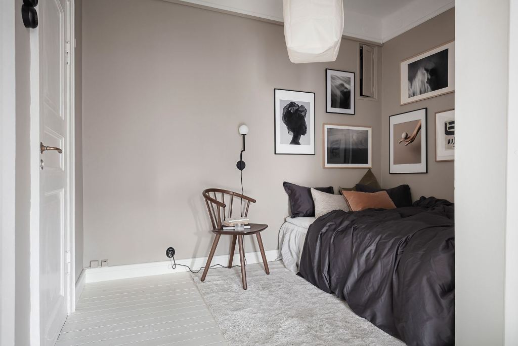 A small bedroom with beige walls and a gallery wall