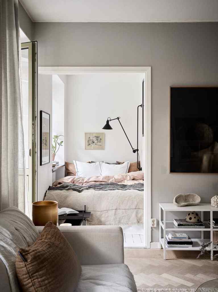 A tiny bedroom that fits the bed exactly, back wall lamp, window towards the kitchen